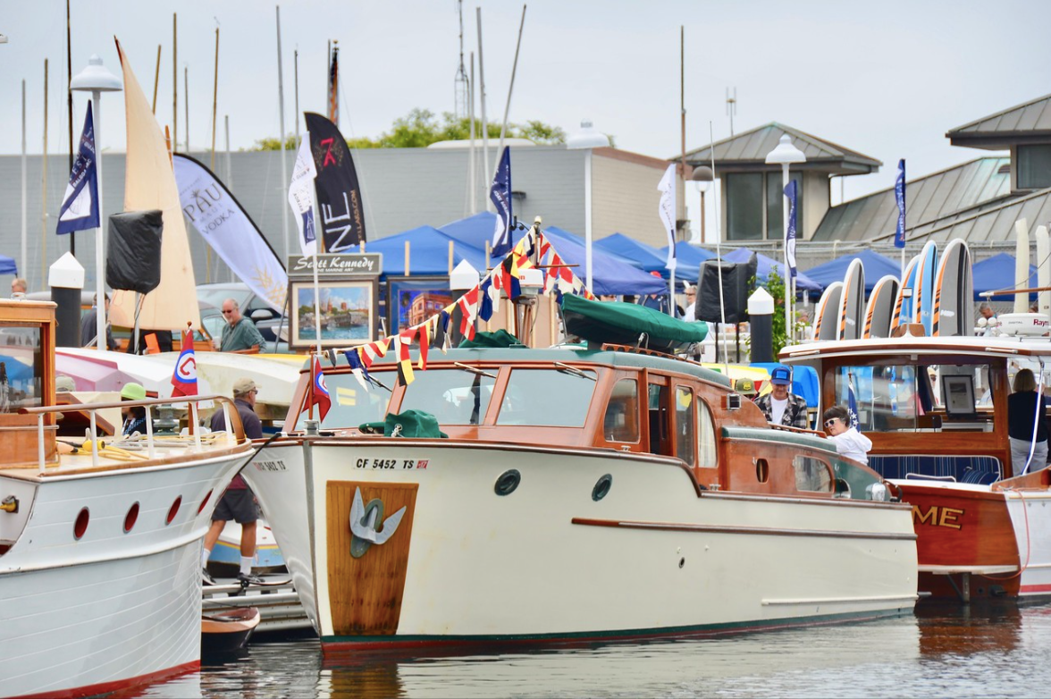 Several boats docked at a harbor with flags and masts