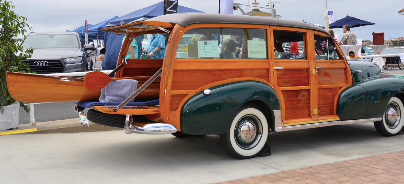 Orange and green vintage woodie wagon parked by the beach with the tailgate open