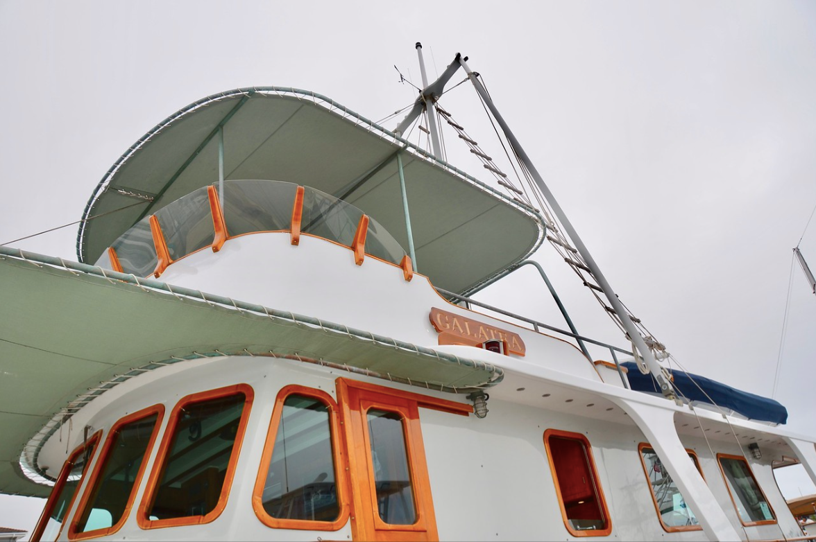 White boat deck with green canopy and orange-trimmed windows against a cloudy sky