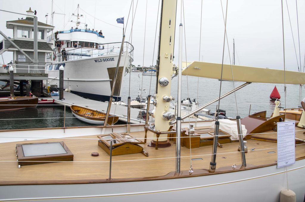 Docked sailboats at a marina with wooden deck, white yachts, and calm water under an overcast sky