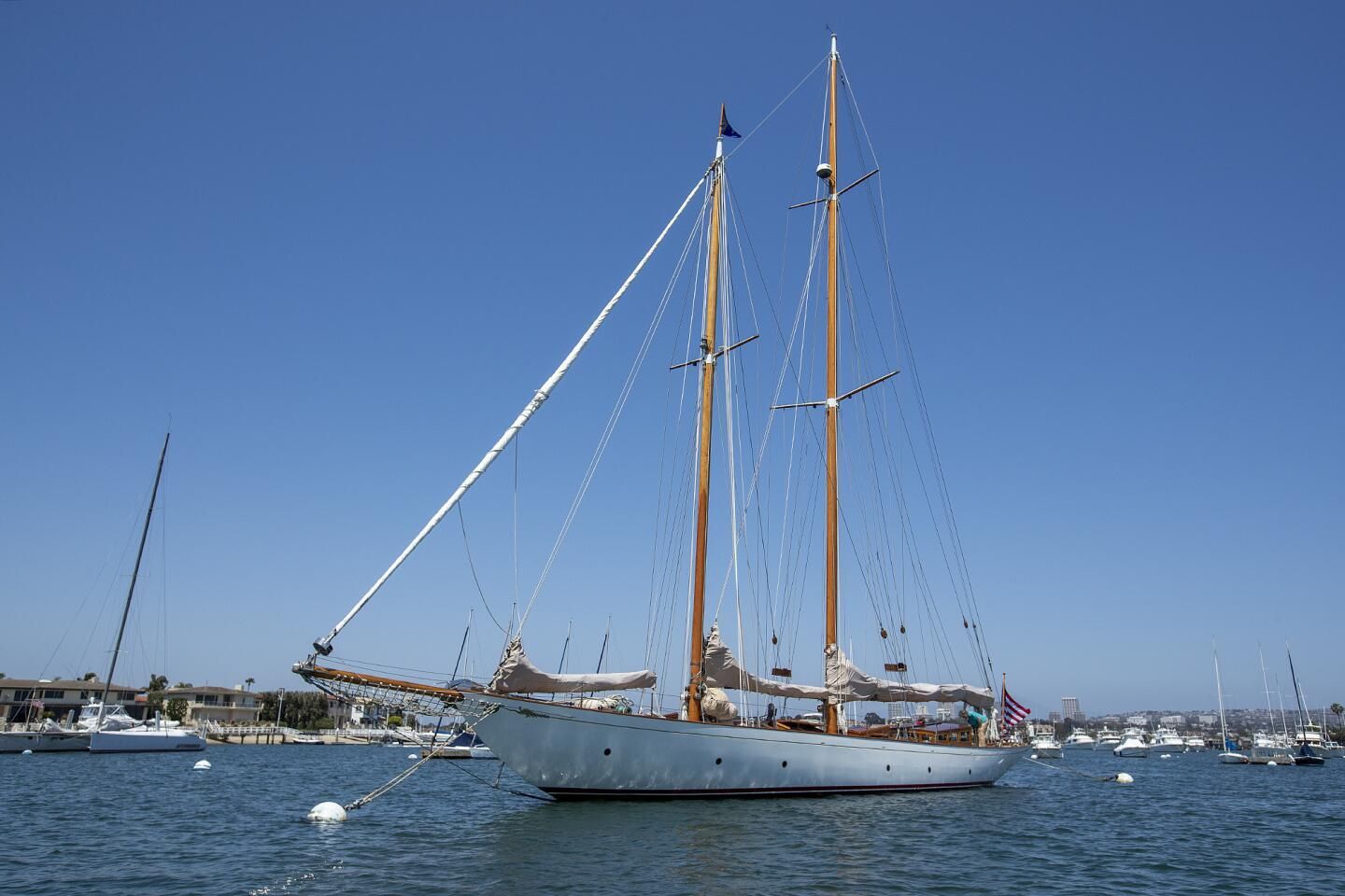 Sailboat docked in calm blue water under a clear sky, with masts and rigging visible.