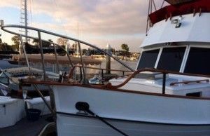 White boats docked at a marina at sunset, with calm water and railings in the foreground