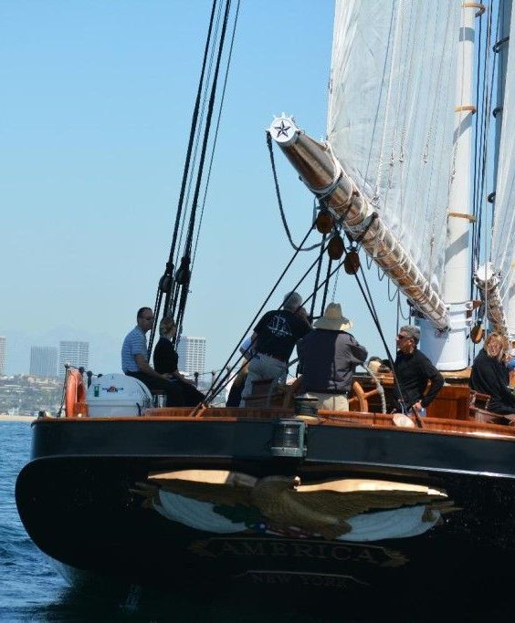 Sailboat bow with crew handling rigging on a sunny day at sea
