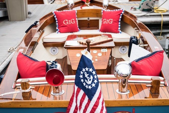 Red and white cushioned boat cockpit with nautical decor and an American flag at the bow