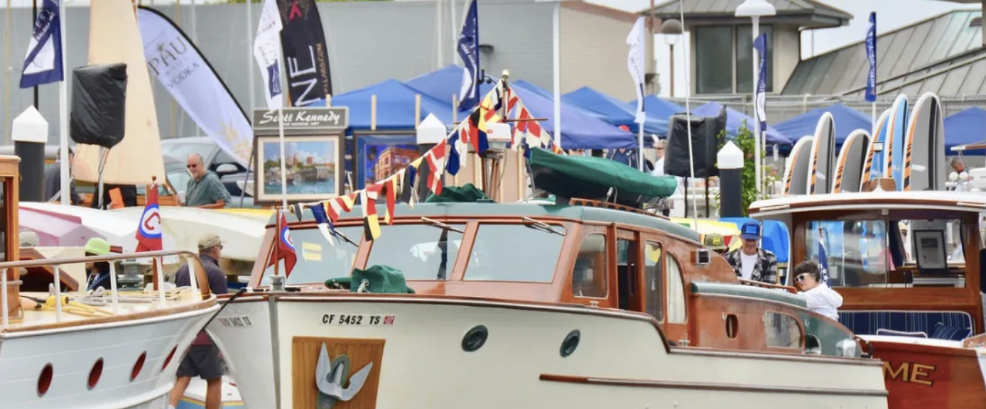 Docked wooden boats with flags and people at a busy marina