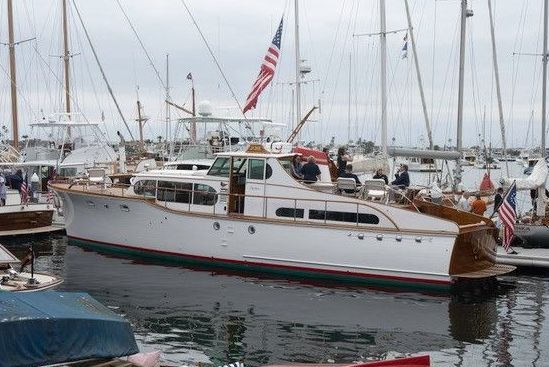 White sailboat with an American flag docked in a marina, surrounded by other boats and masts