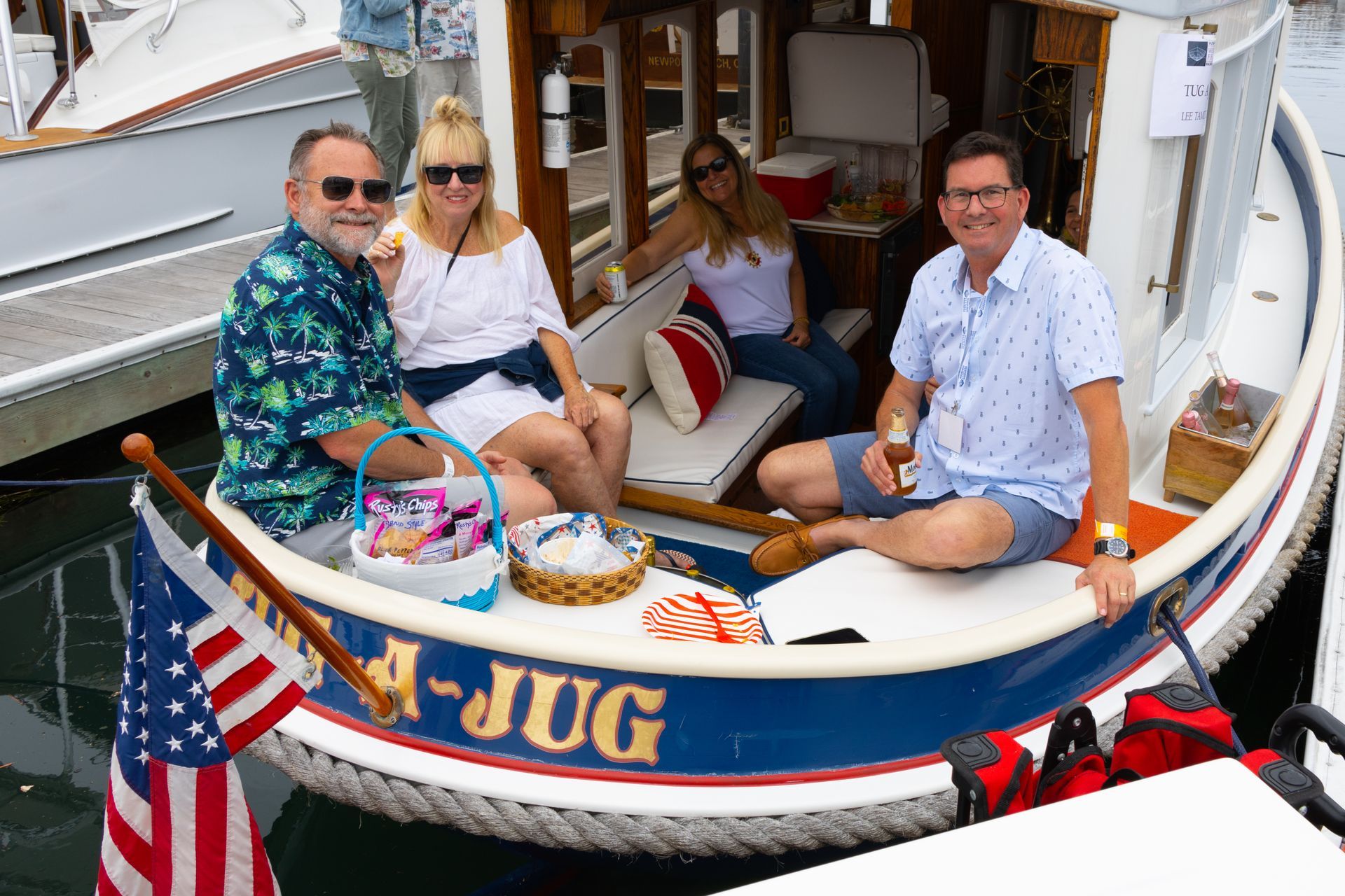 Three people sitting on a small boat at the dock, with an American flag and colorful decorations.