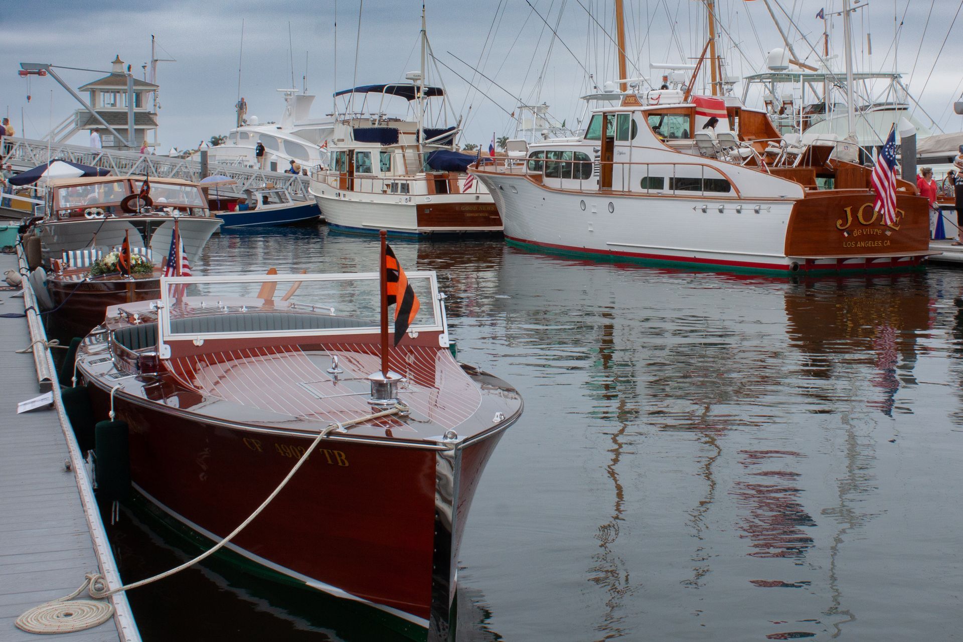 Fishing boats moored in a harbor, including a red boat in the foreground and white boats behind it.