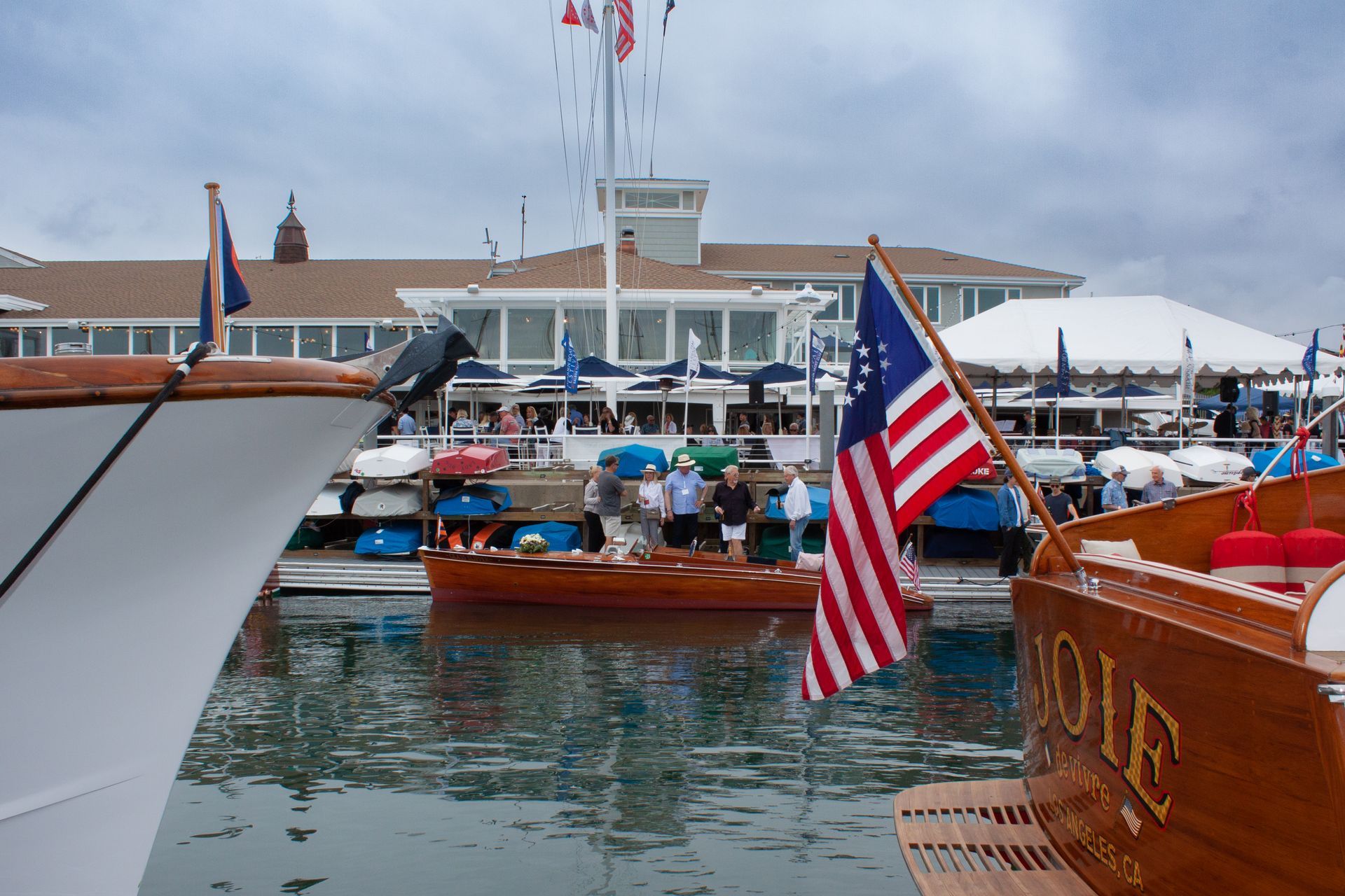 Busy marina with boats, American flags, and a waterfront building in the background