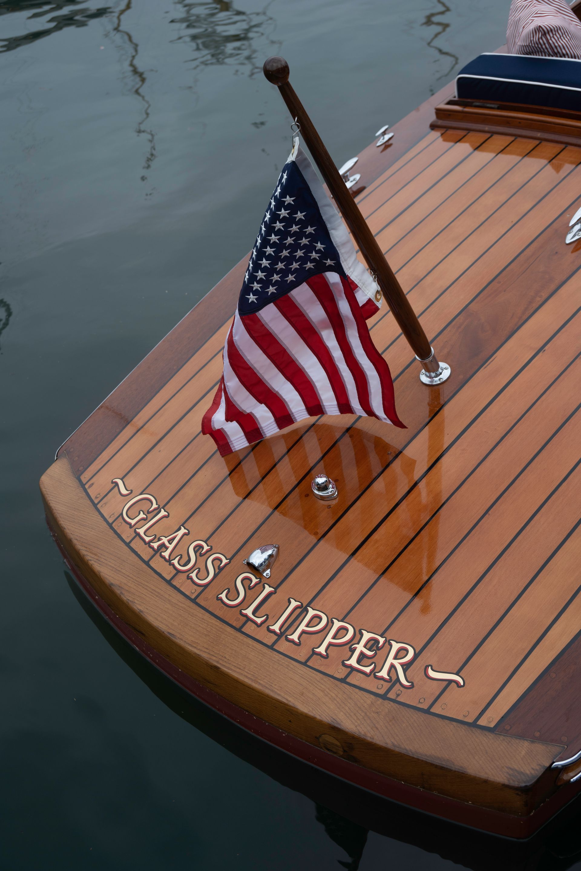 American flag on the stern of a wooden boat named “GLASS SLIPPER” on calm water
