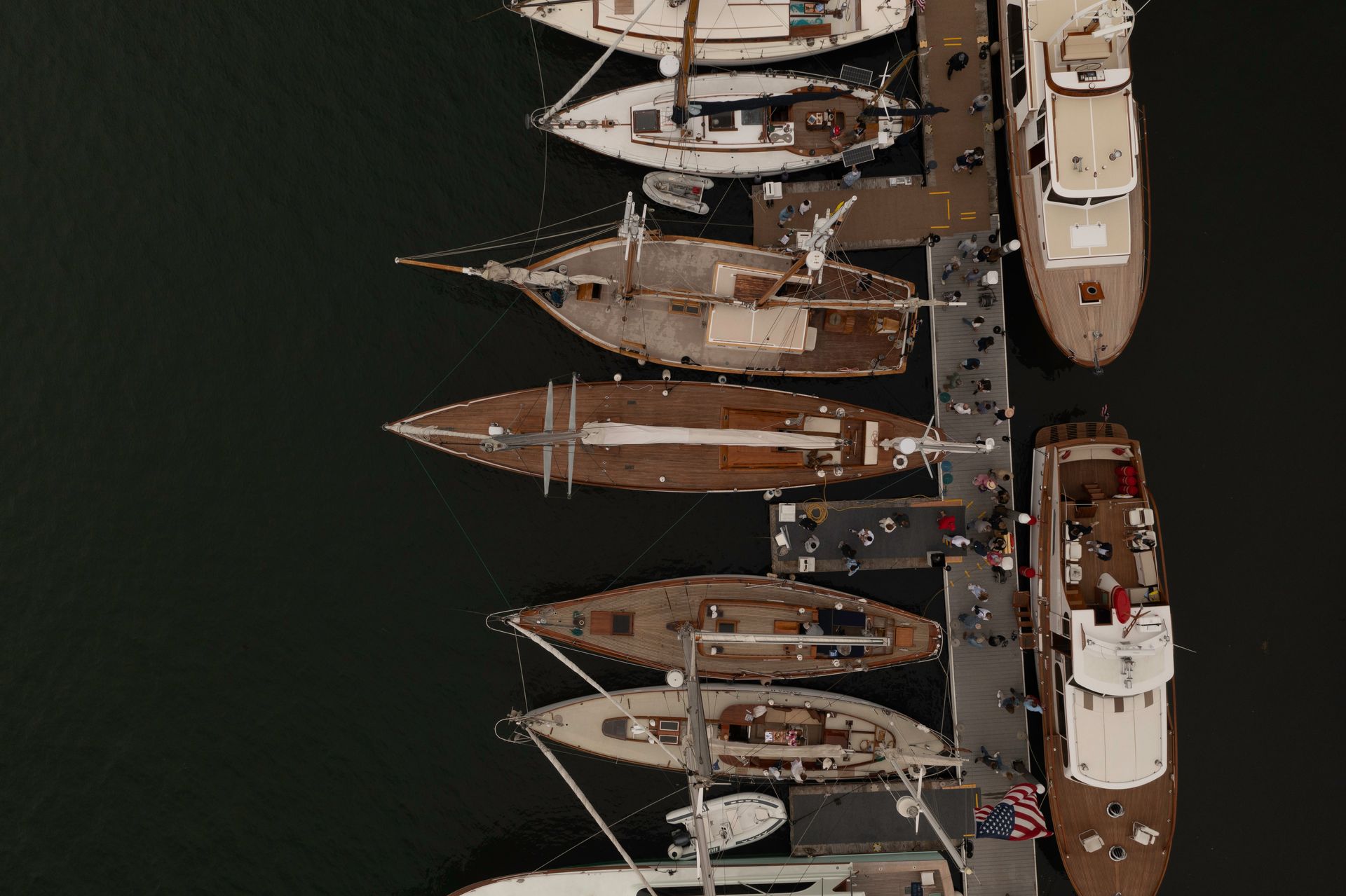 Overhead view of several docked sailboats and yachts along a marina pier at night