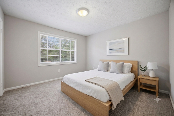 Minimal bedroom with a bed, bedside table, window, and light gray walls