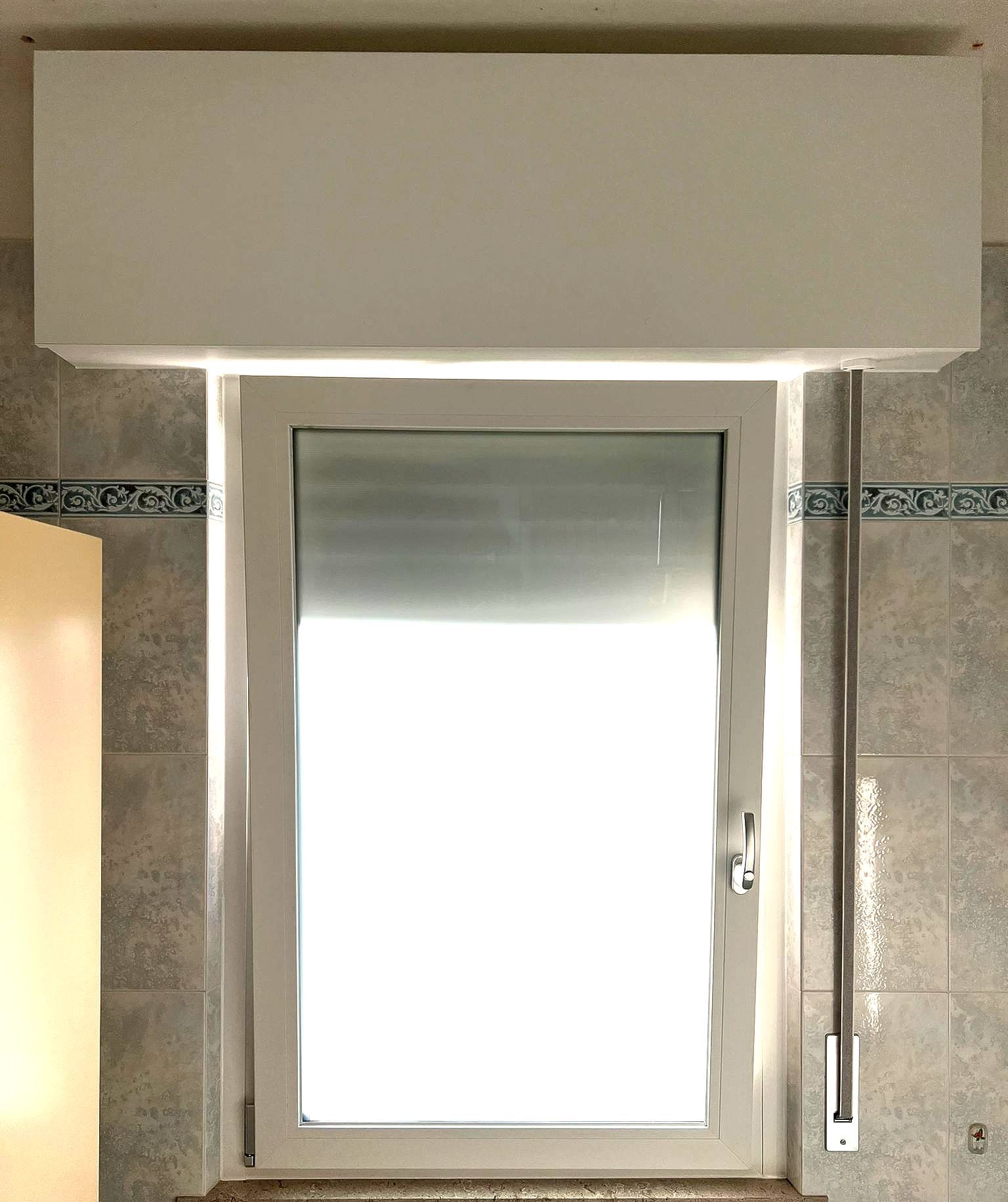 Una finestra bianca con una persiana in un bagno.
