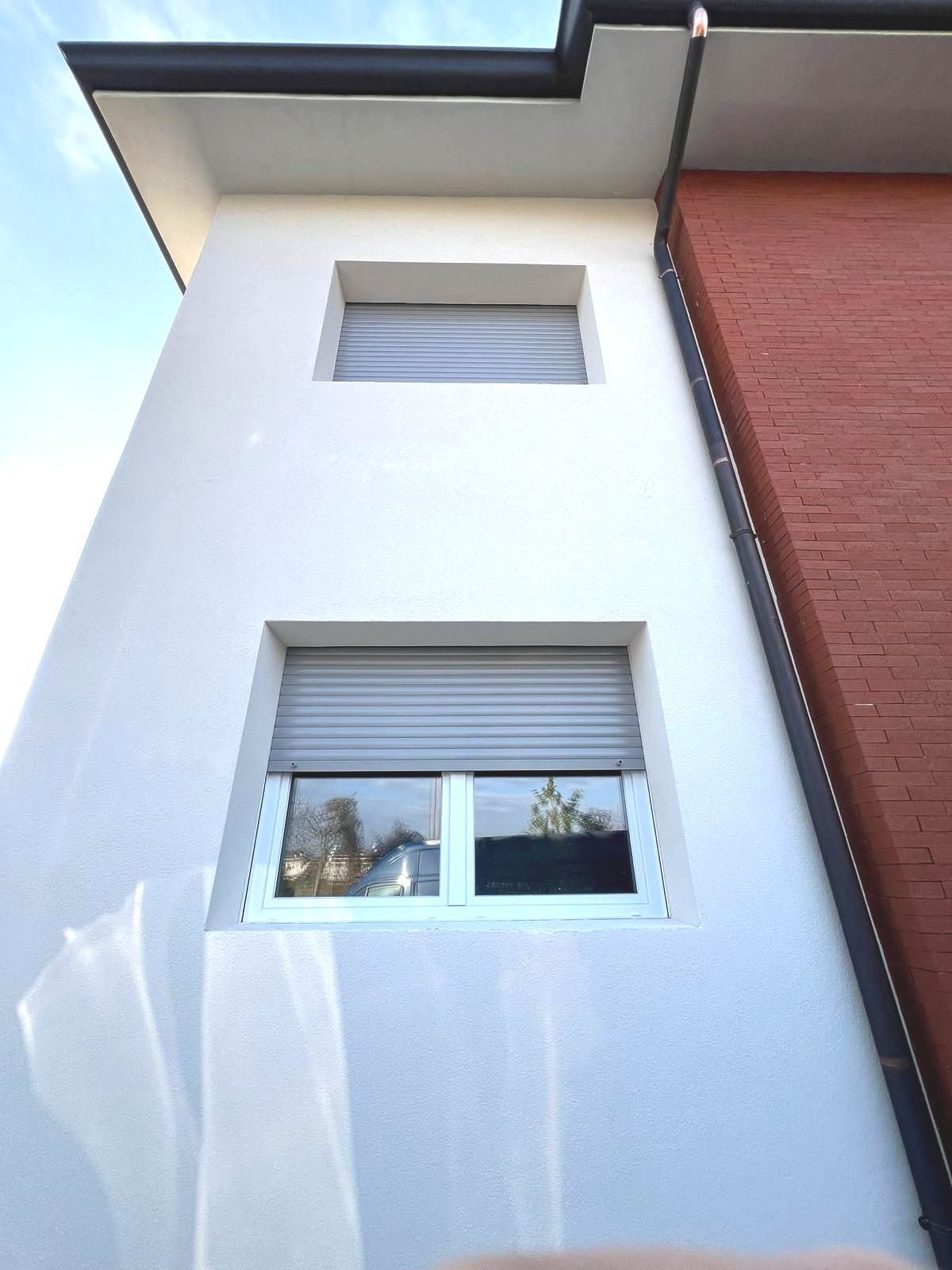 Un edificio bianco con un muro di mattoni rossi e due finestre