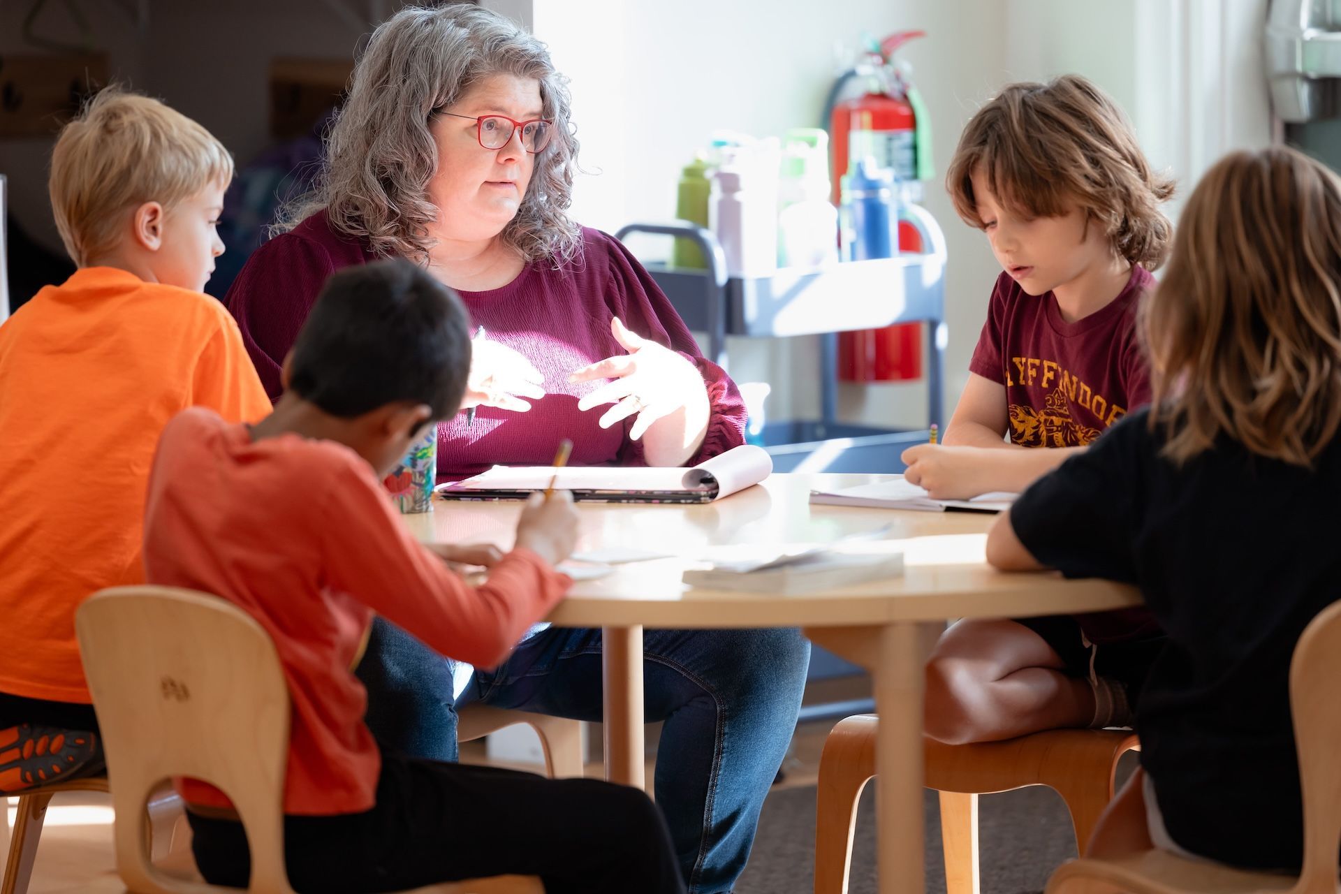 Teacher leading a small classroom discussion around a table with children working together