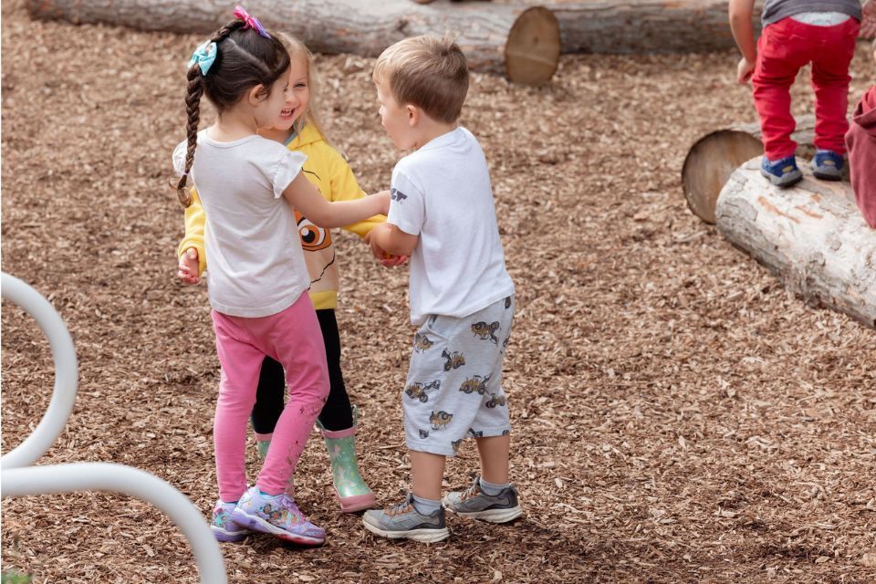Montessori children playing together outside, learning empathy, cooperation, and friendship skills.
