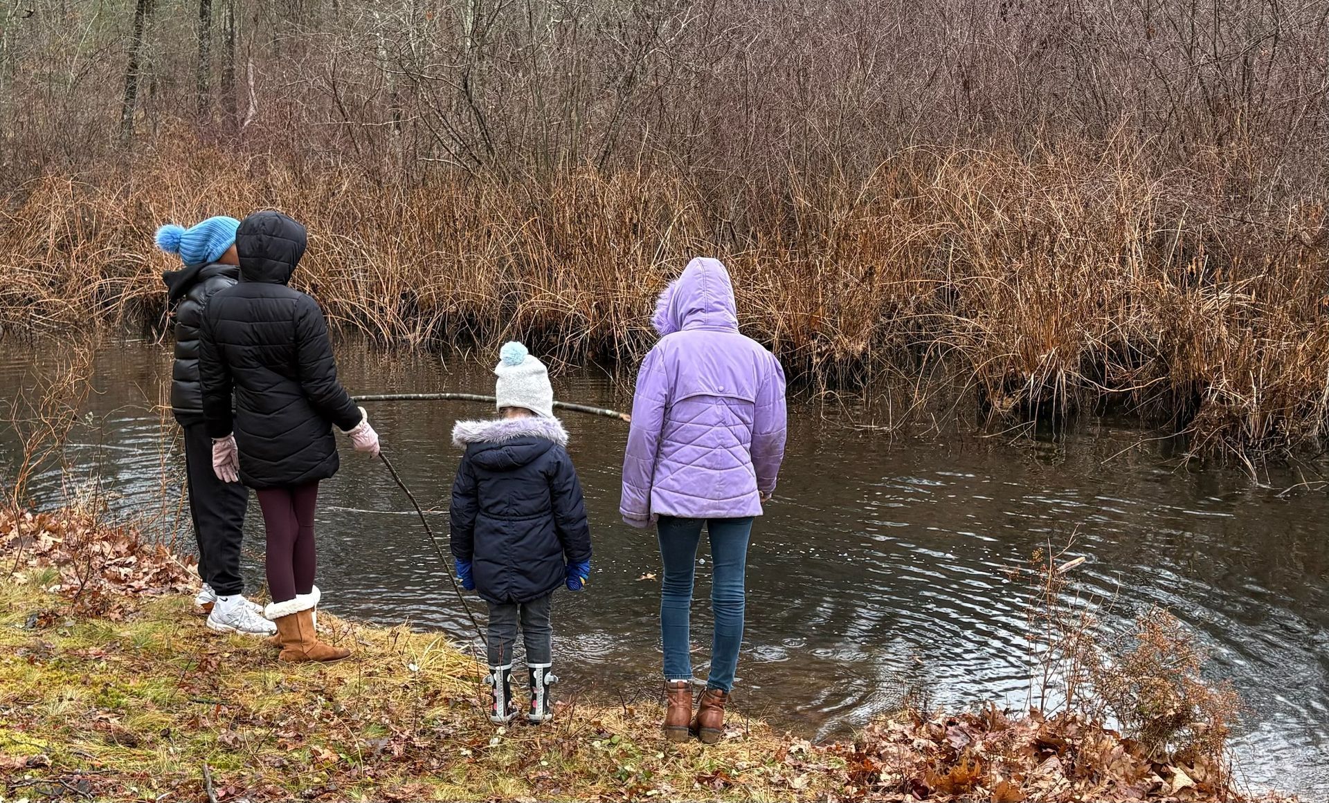 A group of Montessori children are standing next to a river.