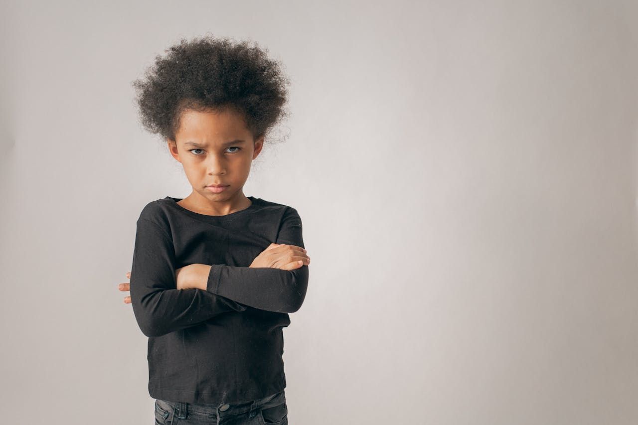 Young person with arms crossed, frowning.