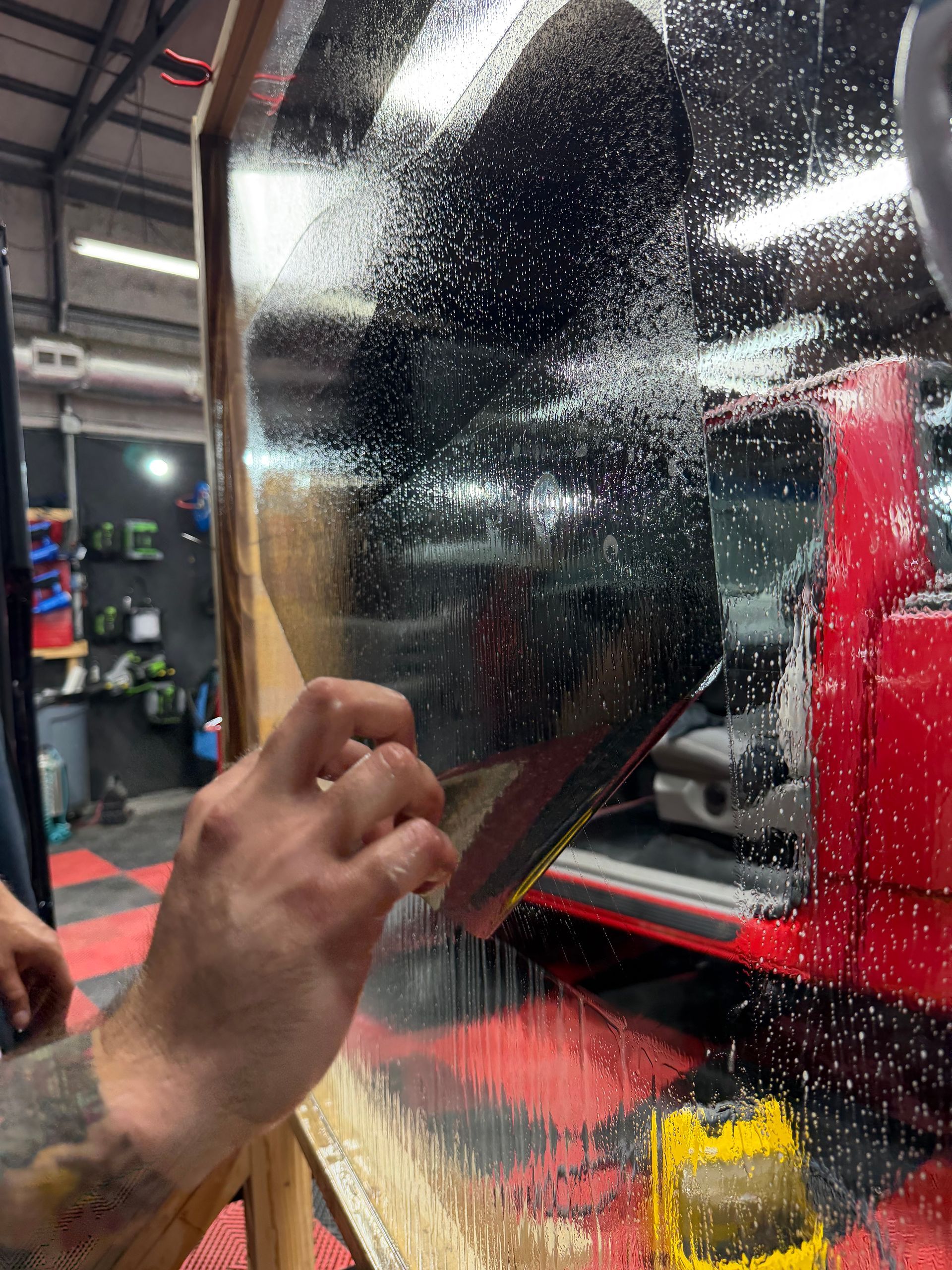 Person cleaning a car windshield with a wiper on a rainy day