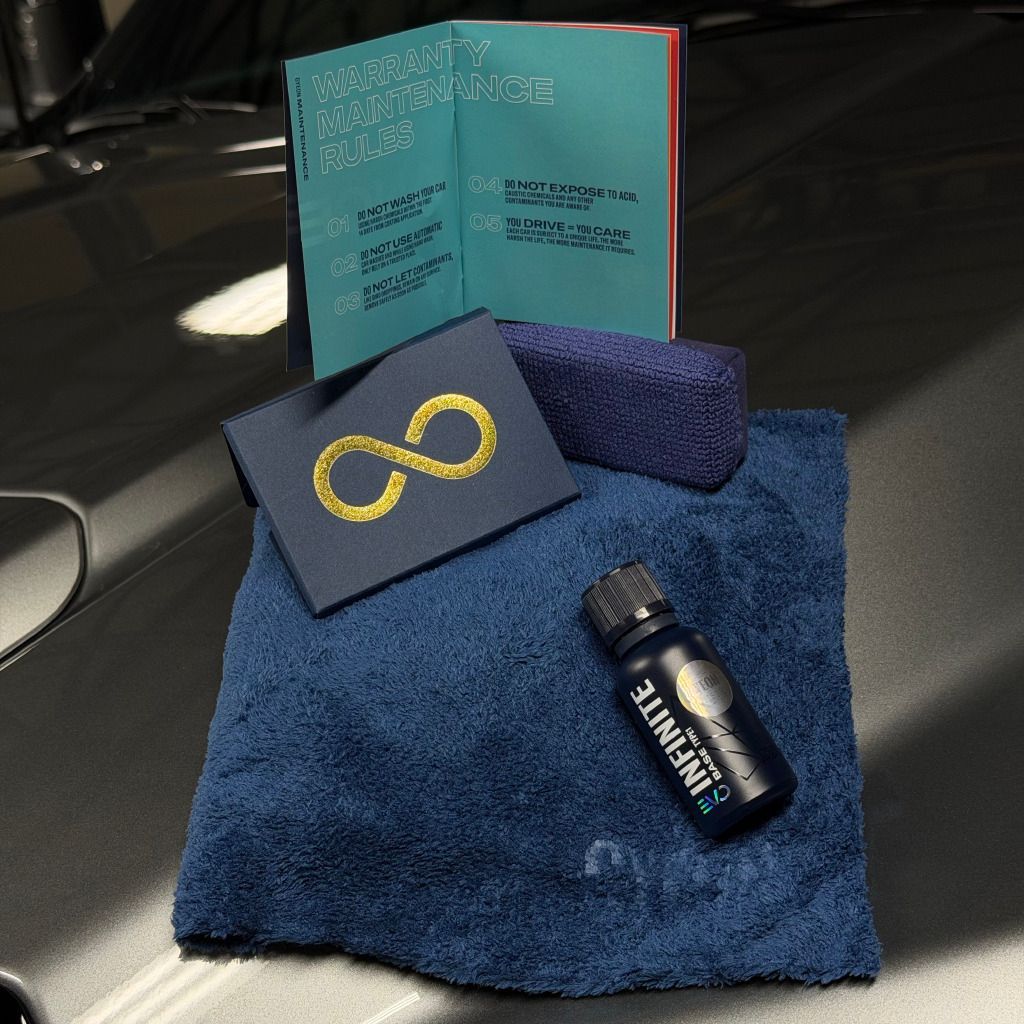 Blue towel with a dark bottle and card, beside an open teal box on a car hood.
