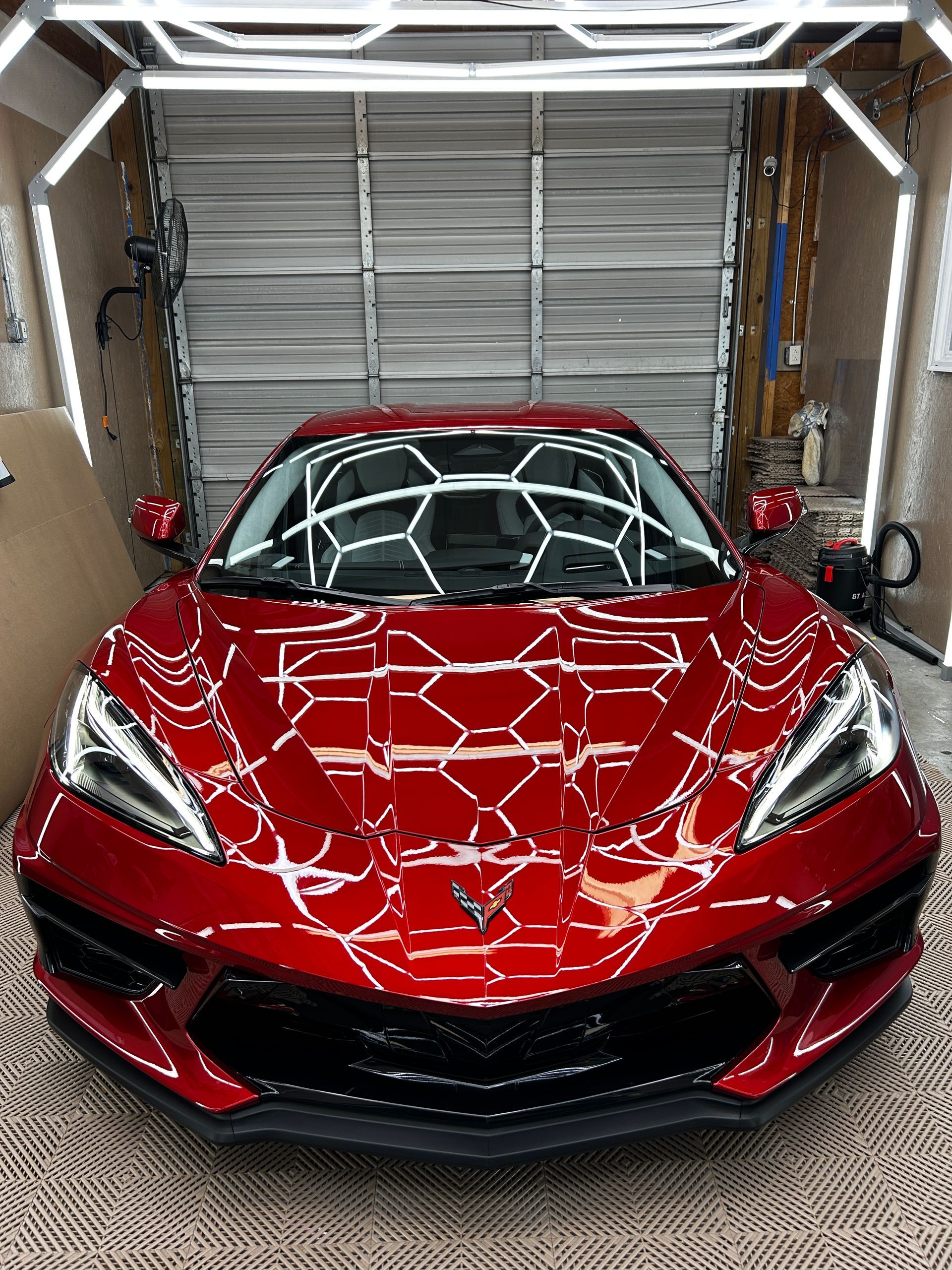 Person applying window film to a dark blue car in a workshop