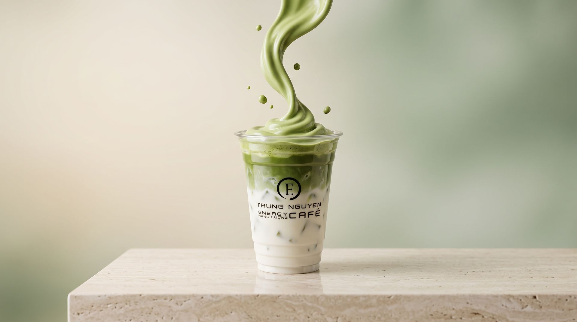 Iced matcha latte topped with swirling green foam on a light stone table against a soft green background