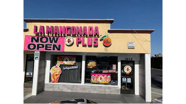 Storefront with bright pink “Lamangonada Now Open Plus” sign above windows and a white awning.