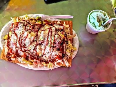 Loaded fries topped with sauce on a tray beside a small cup of dipping sauce