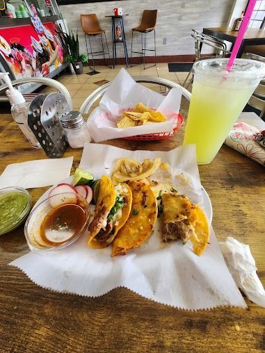 Tacos, chips, and drinks on a table in a casual restaurant setting