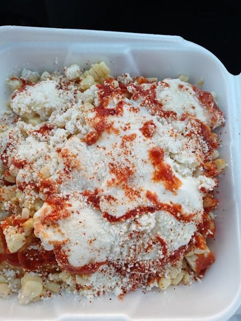 Container of pasta topped with grated cheese and red sauce seasoning