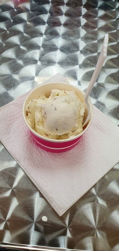 Cup of vanilla ice cream on a pink napkin atop a shiny silver table