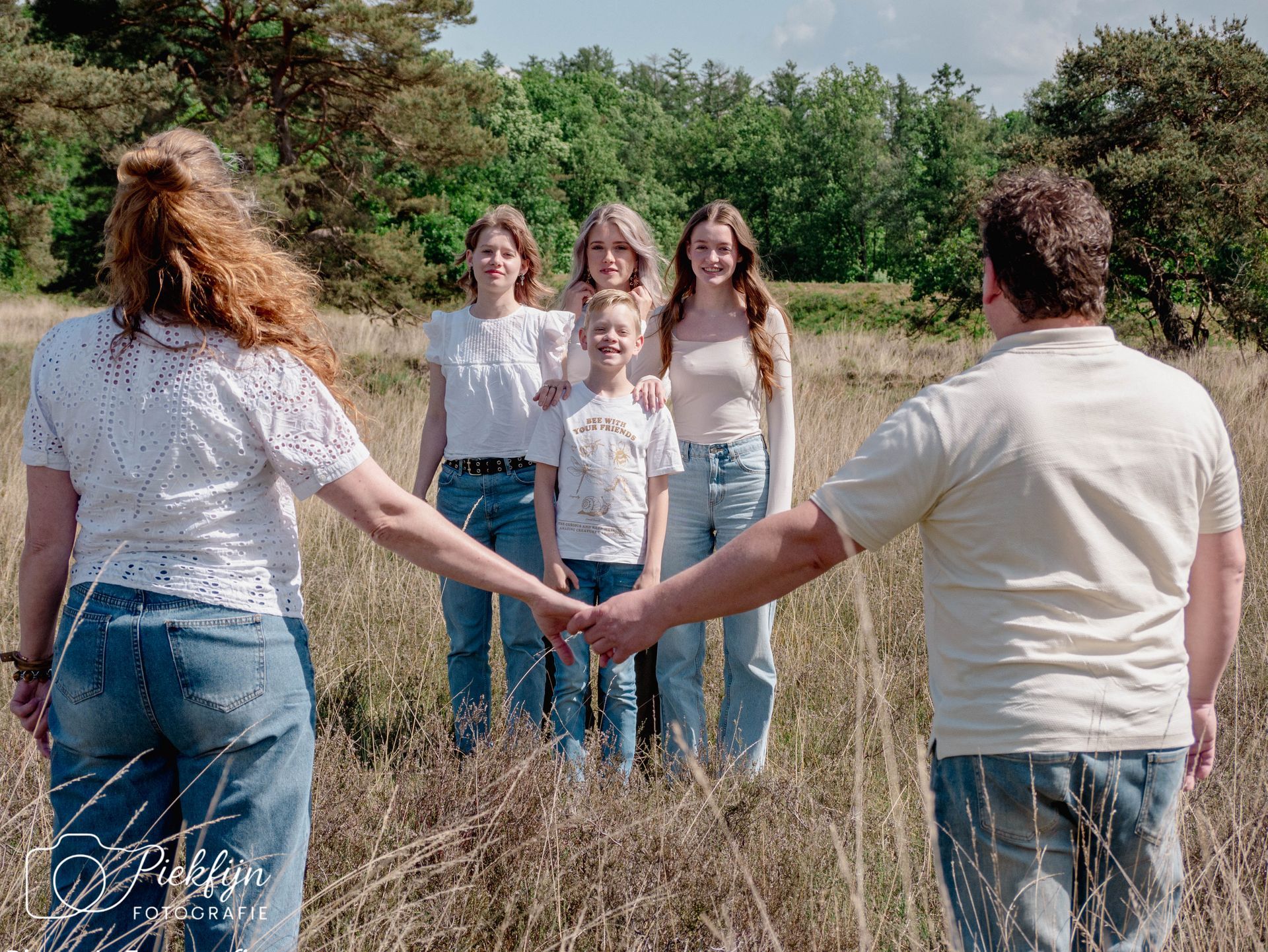 Een groep mensen staat hand in hand in een veld.