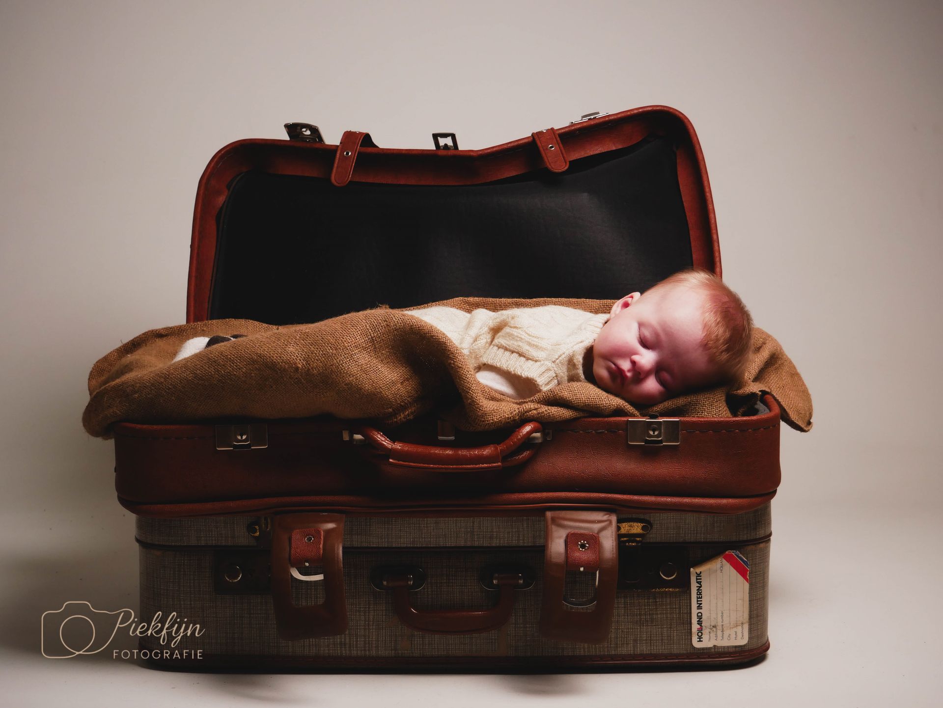 Een baby slaapt in een open koffer.
