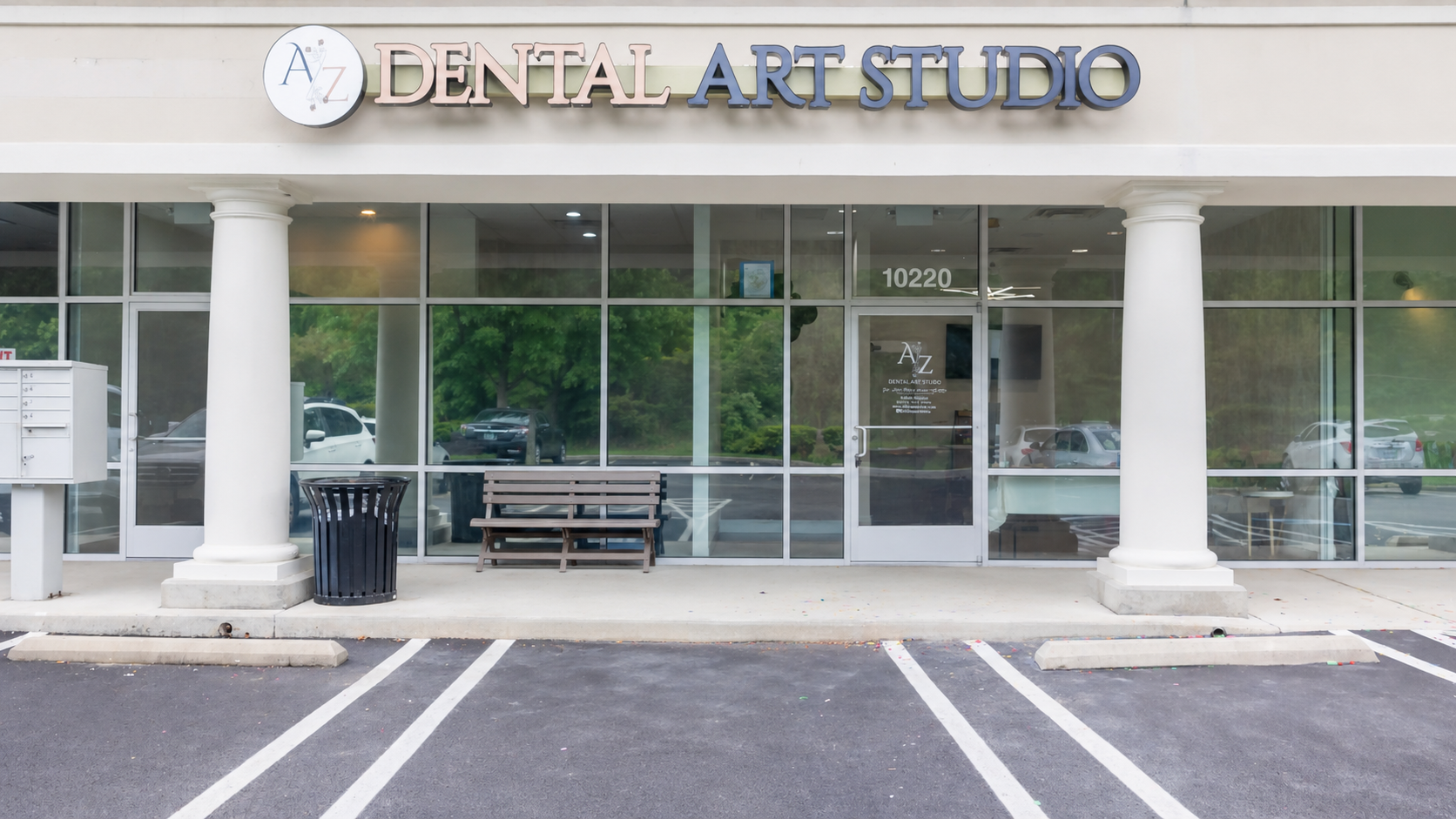 Dental Art Studio storefront with white columns, glass doors, and empty parking spaces in front