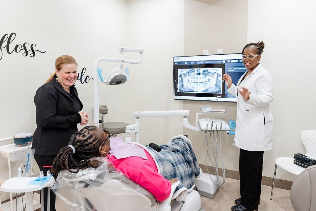 Dentist showing x-ray on monitor to patient in a bright dental exam room