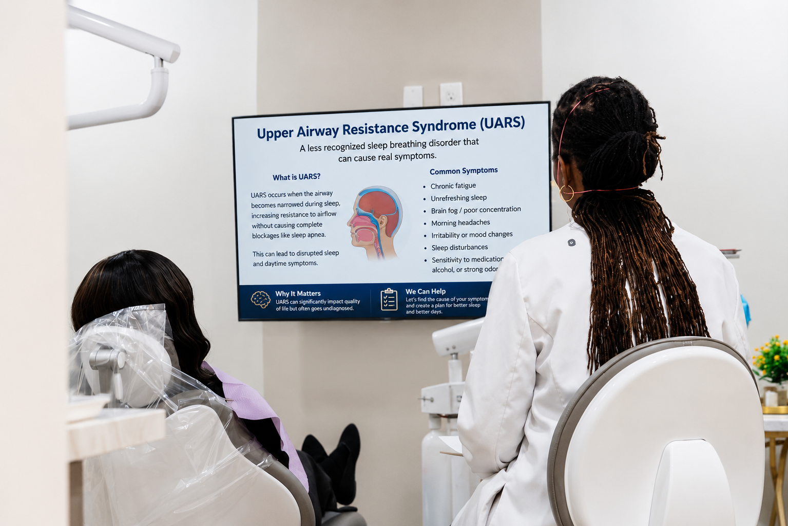 Two people in white coats viewing a brain scan presentation on a wall monitor in a clinic.