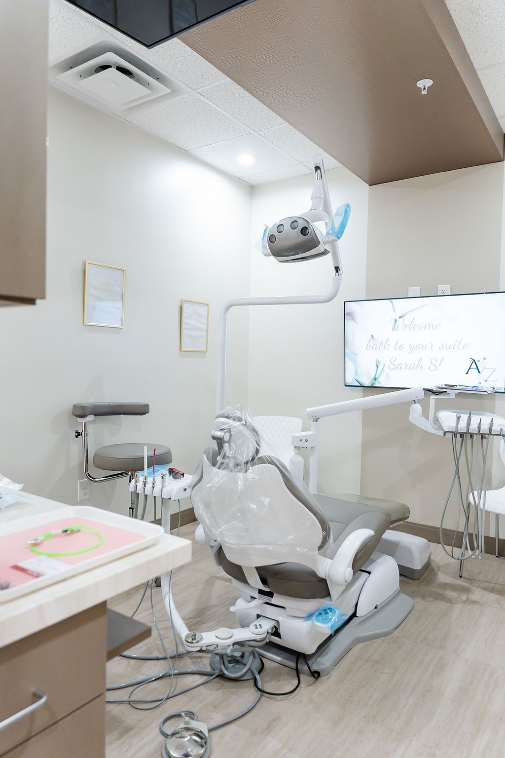 Empty dental treatment room with chair, overhead light, and equipment in a clean white interior