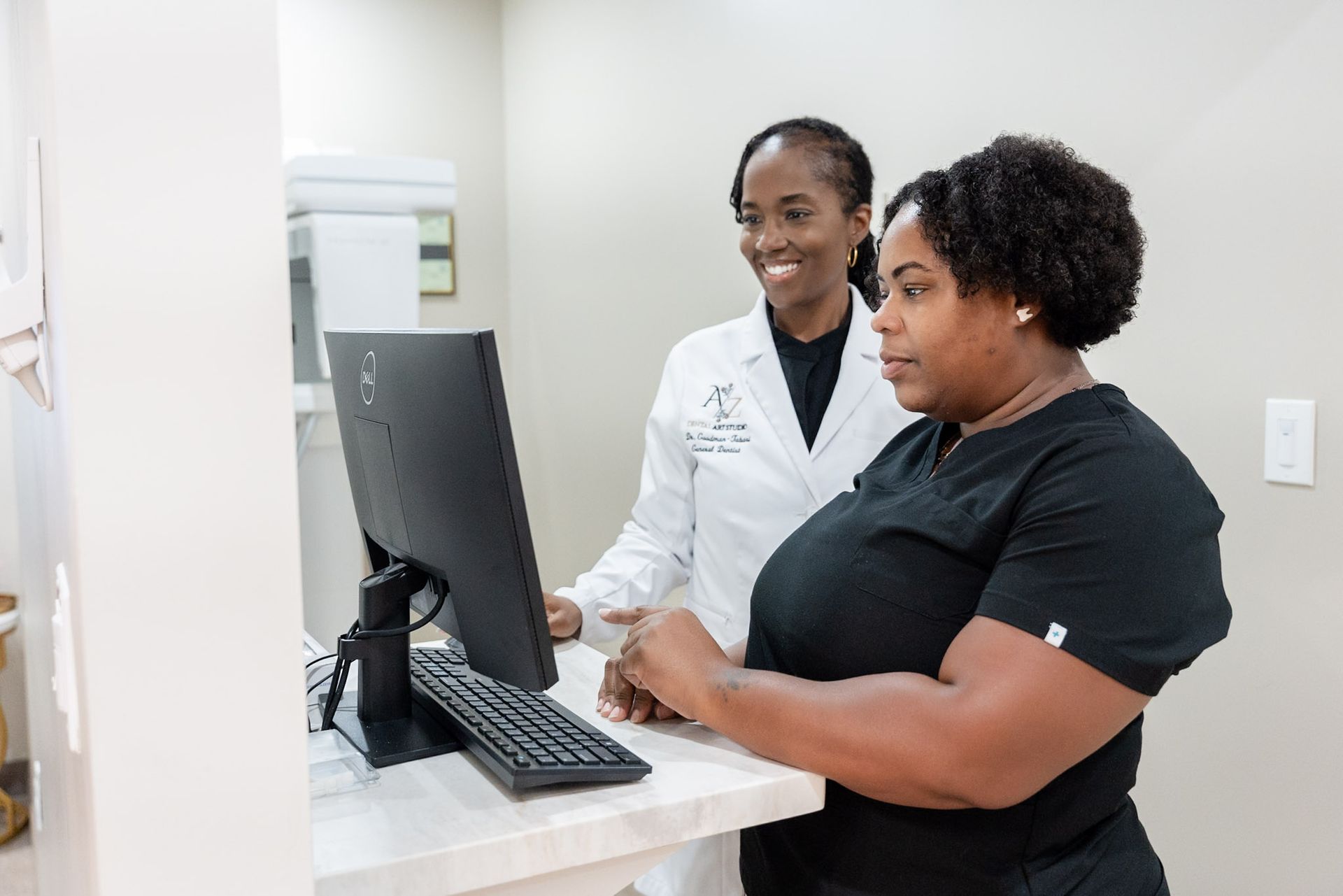 Two women reviewing information on a desktop computer in a clinic office