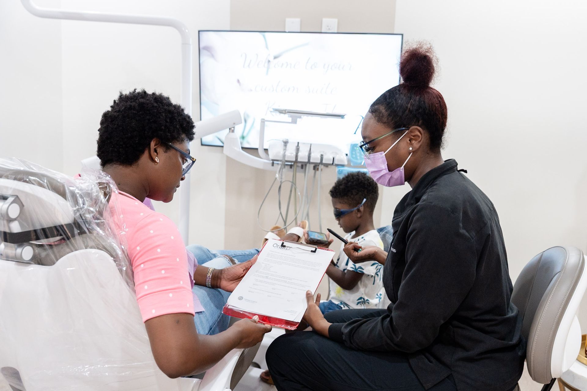 Dental exam with clinician reviewing chart while patient sits in chair