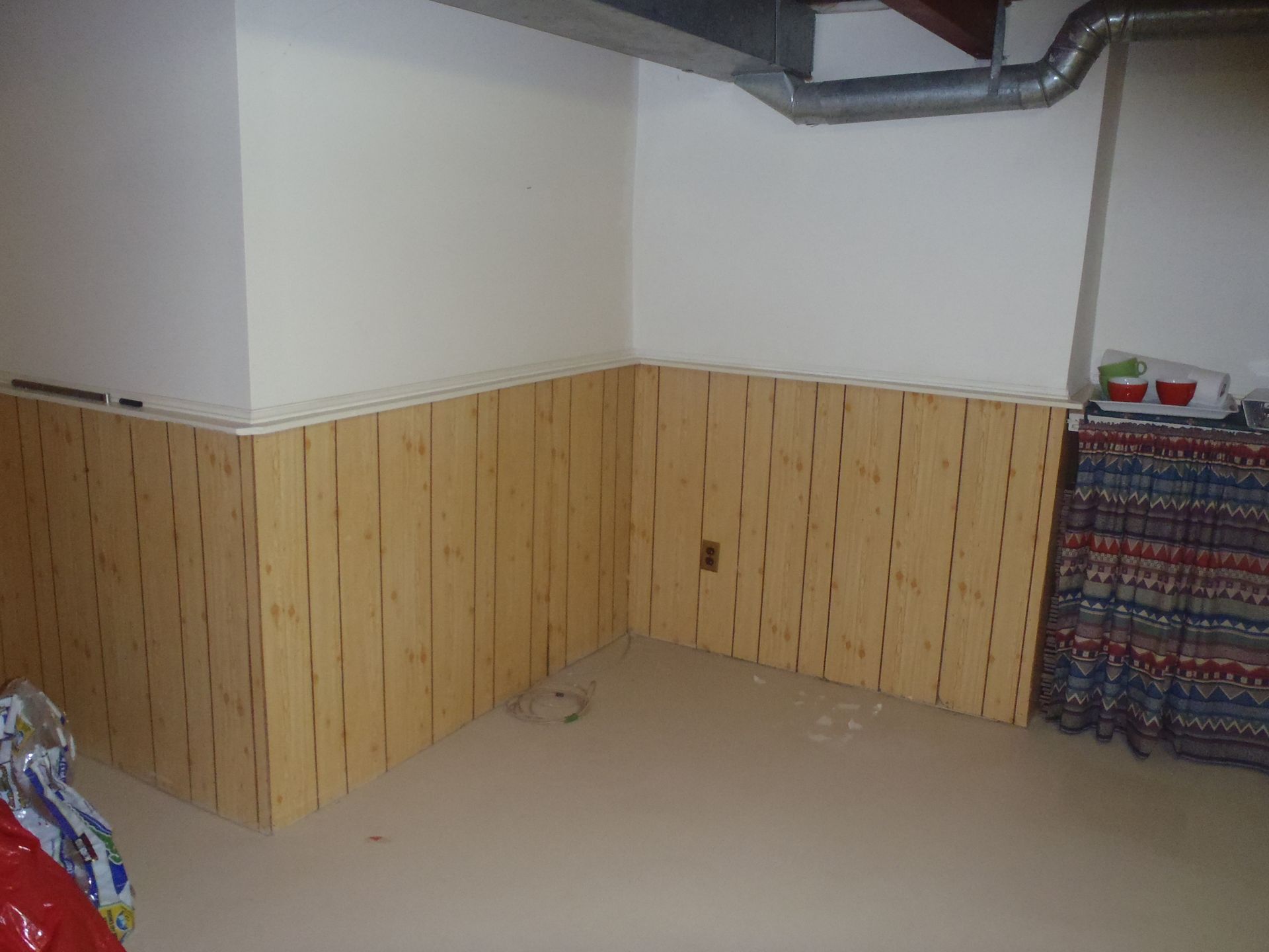 Empty room with beige wood-paneled lower walls and exposed ductwork near the ceiling.