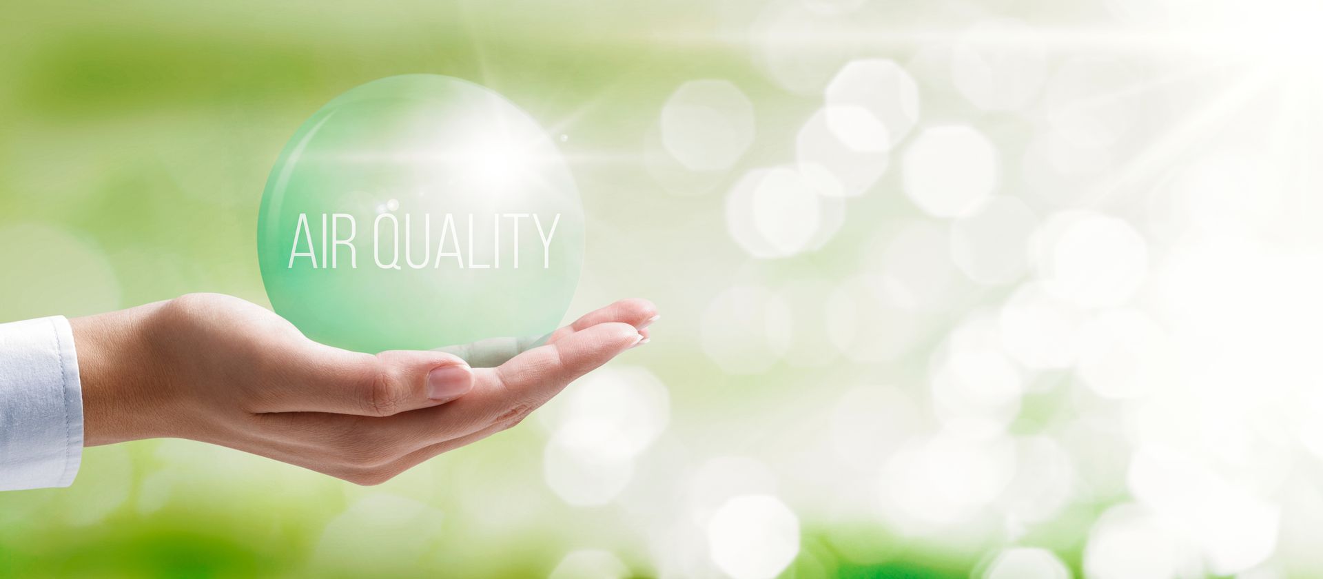 A hand is holding a green ball with the word air quality written on it.