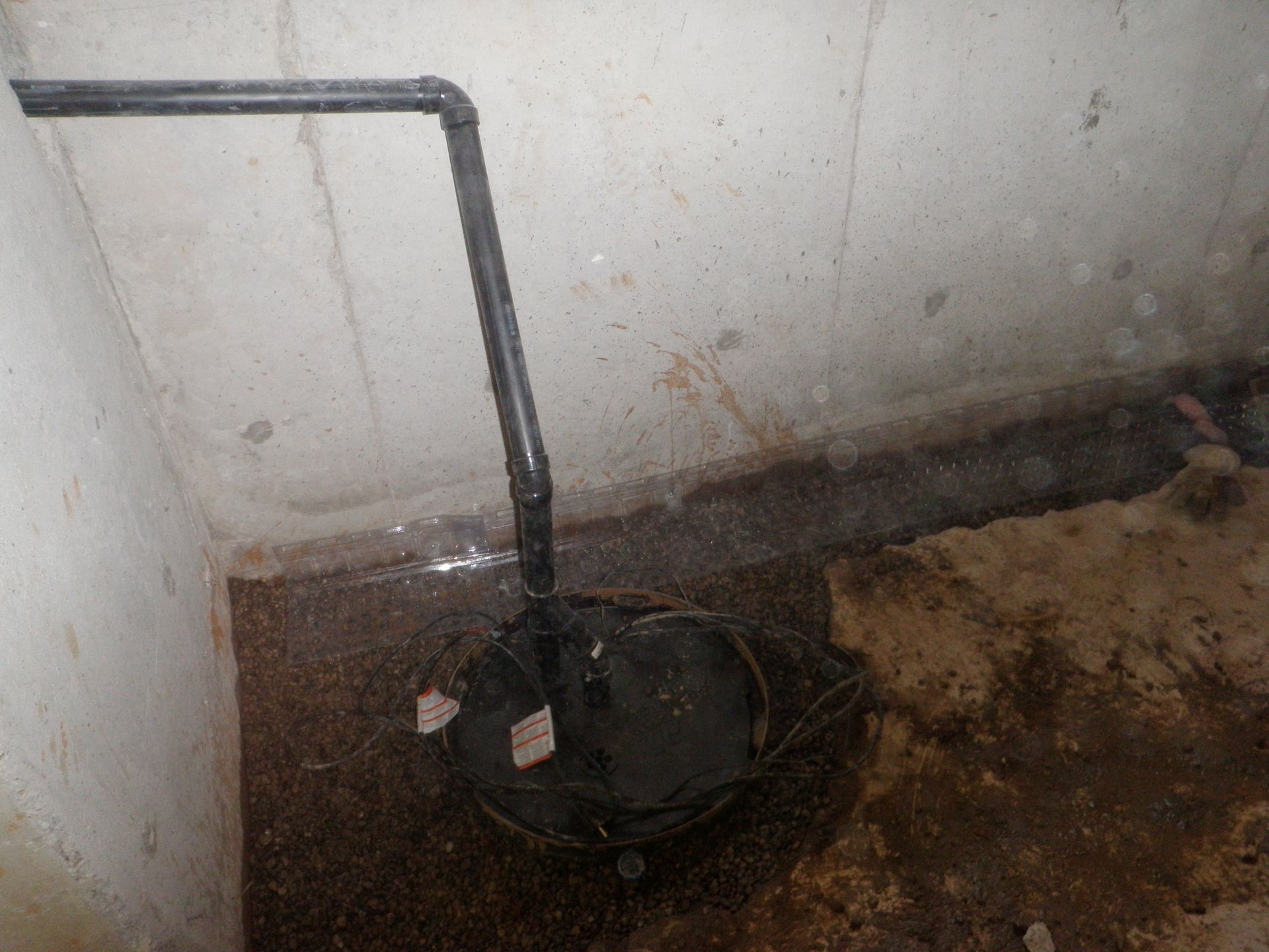 A black pipe is sitting in a corner of a room next to a wall.