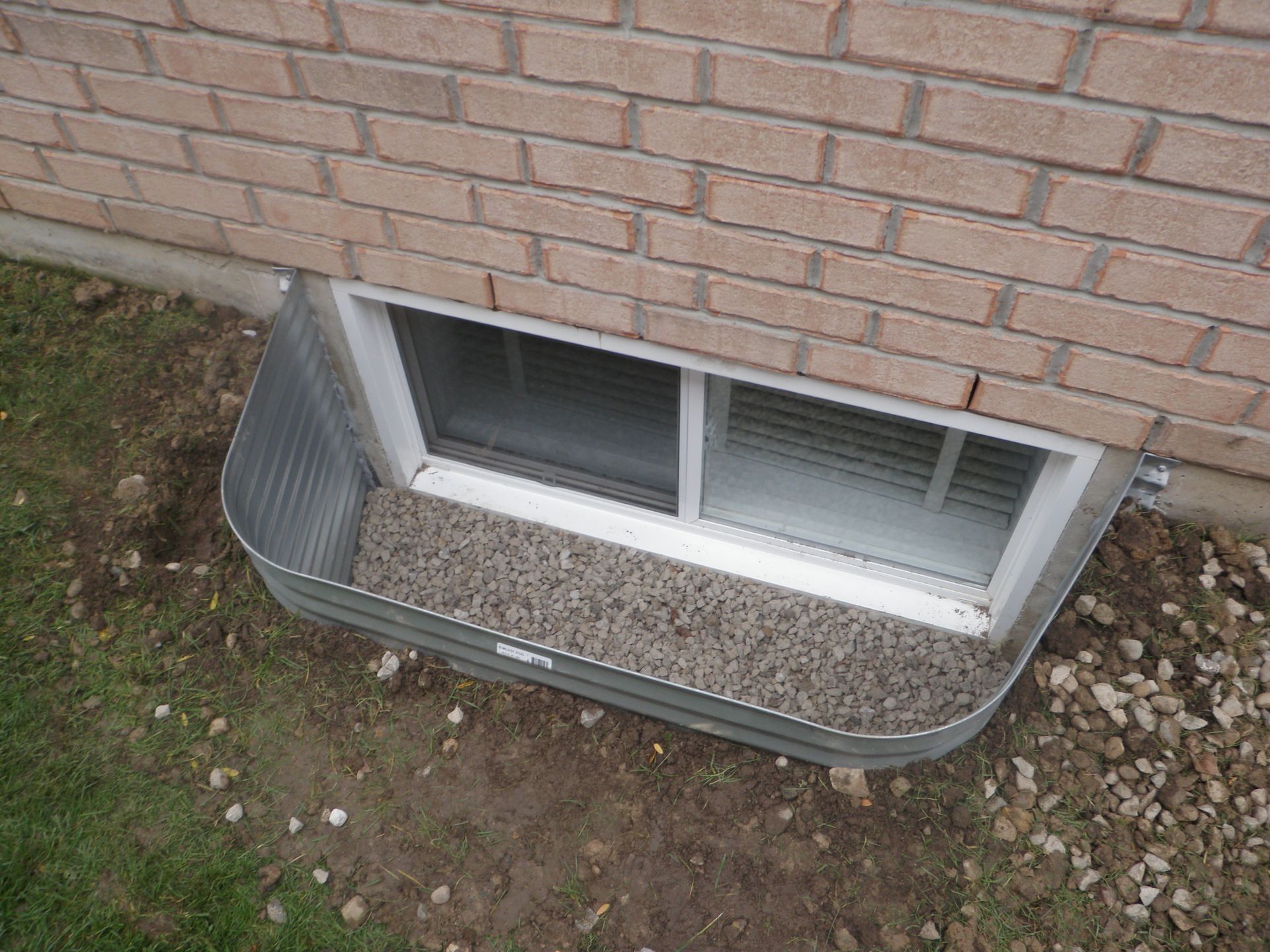 Window well with gravel against a brick building.