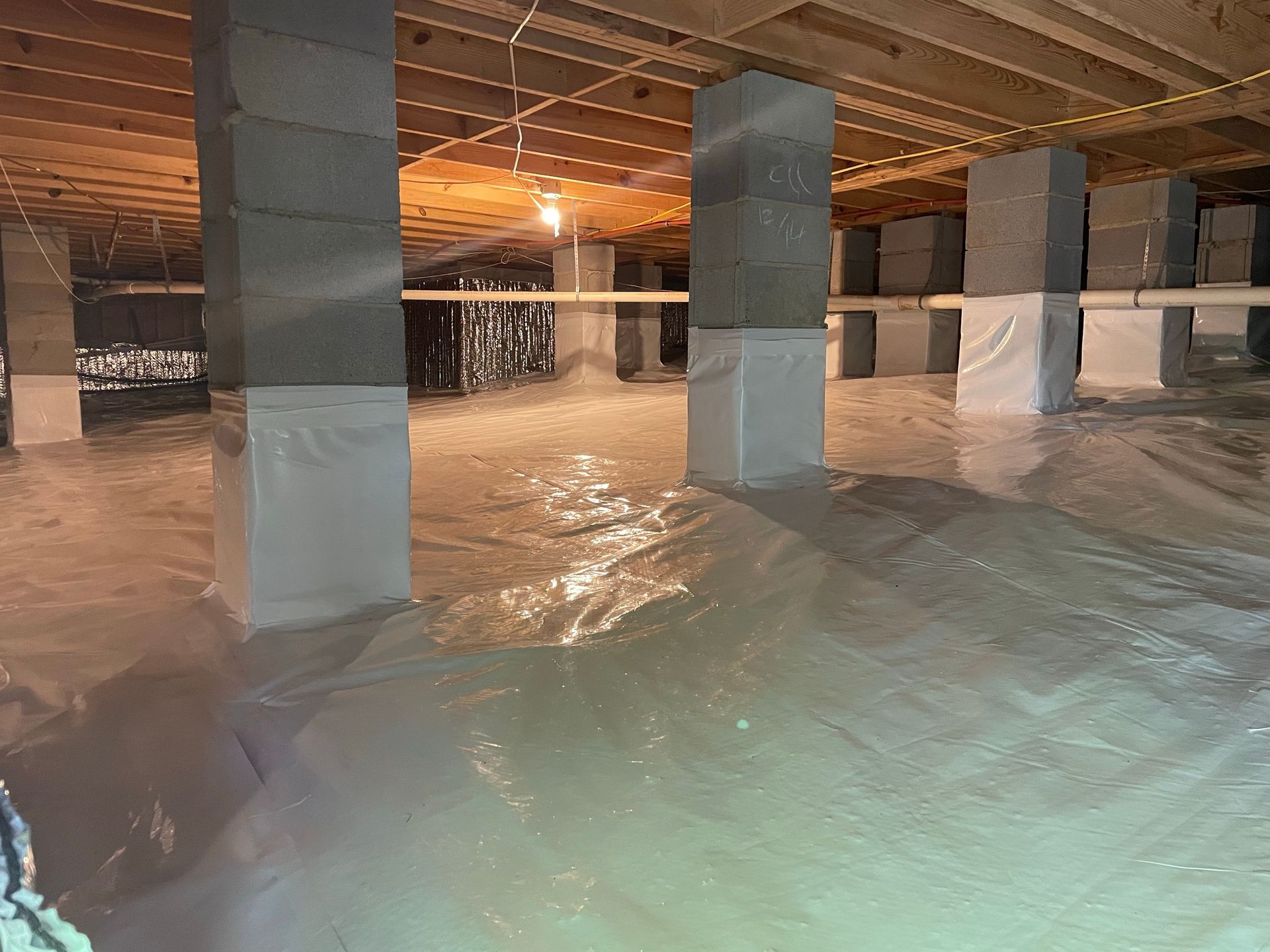 Flooded basement with water covering the floor around concrete support pillars and low ceiling beams.