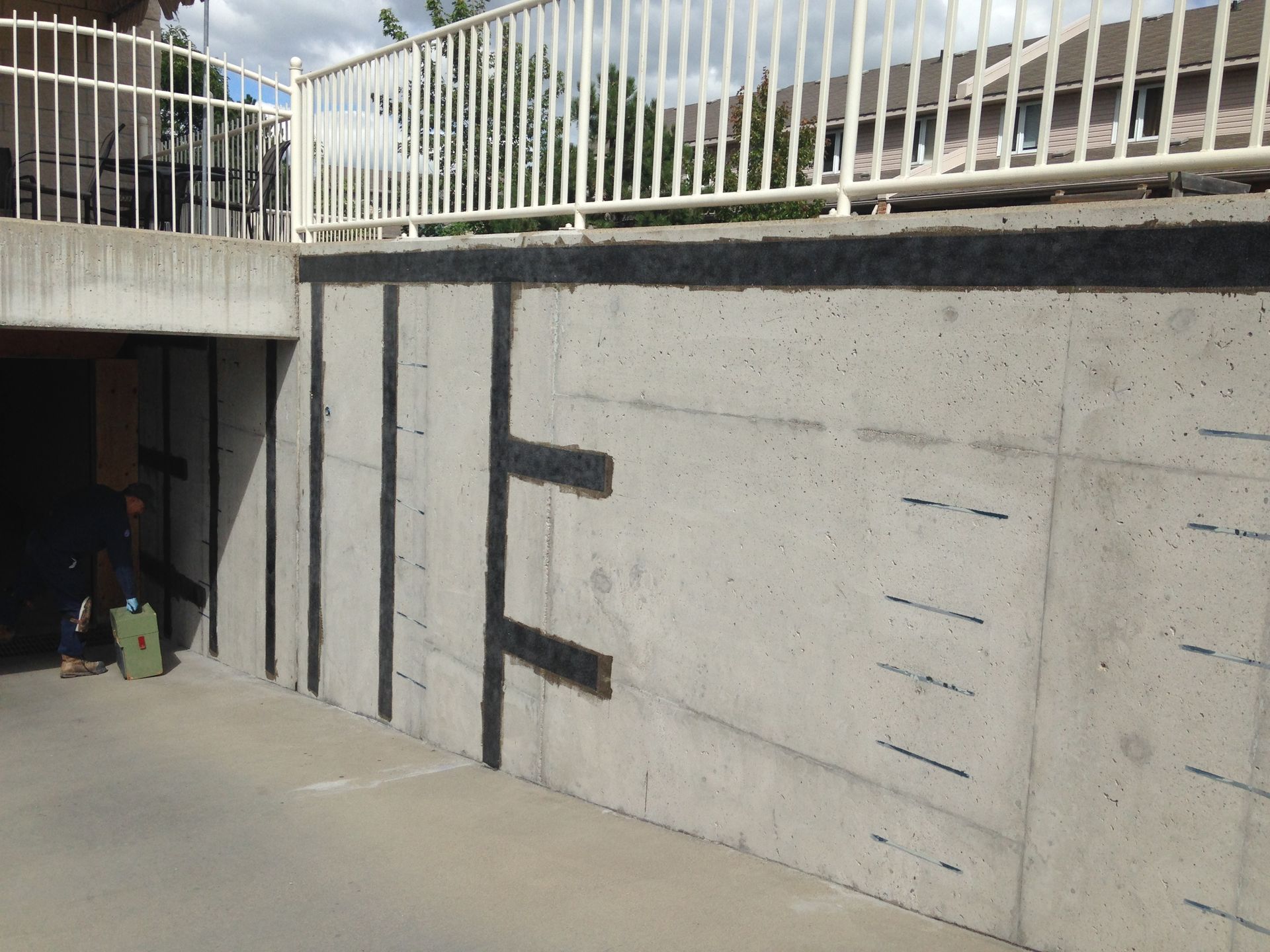 Concrete wall with black stripes and a white railing above. A person stands at the left.