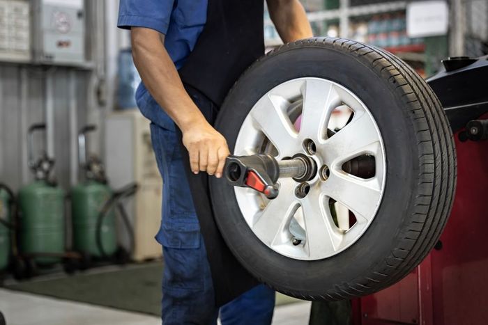 Mechanic balances a tire on a machine in a garage.