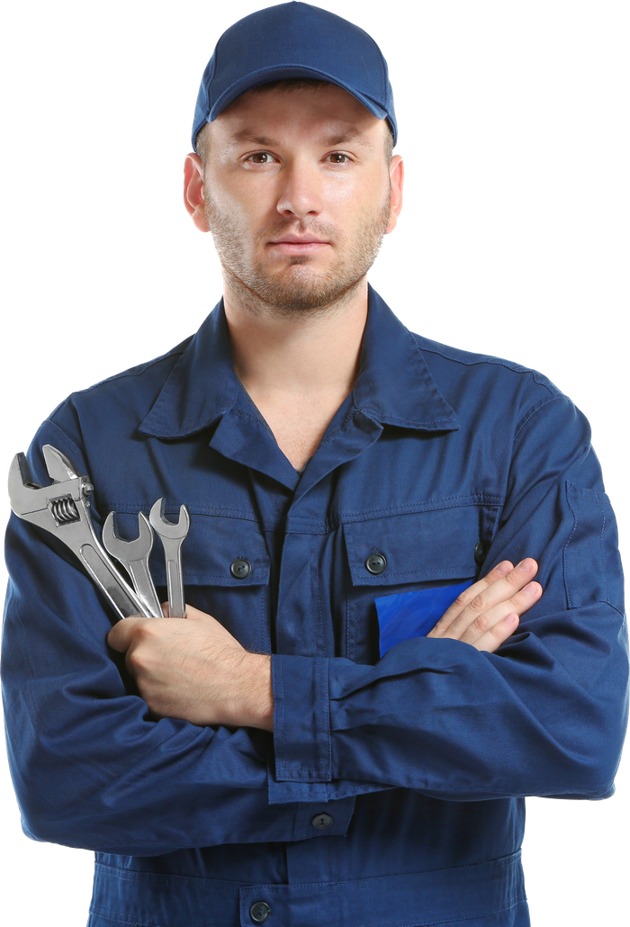 Mechanic in blue jumpsuit and cap holding wrenches with arms crossed.