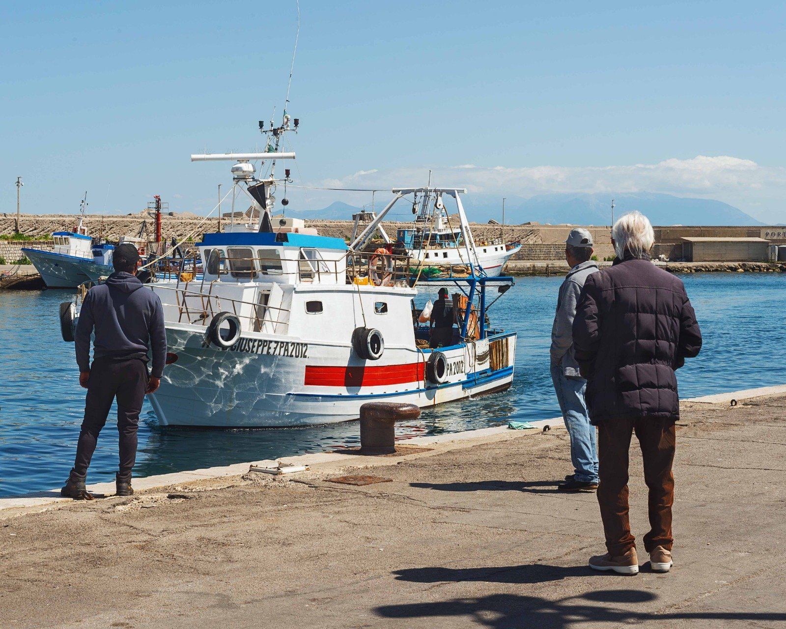 Due uomini sono in piedi davanti a una barca su cui è scritta la parola