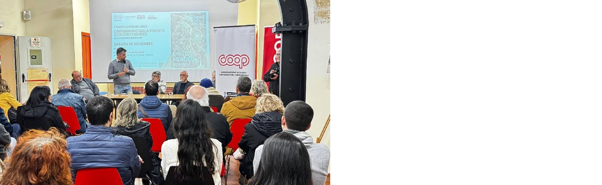 Un gruppo di persone è seduto in una stanza e guarda una presentazione.