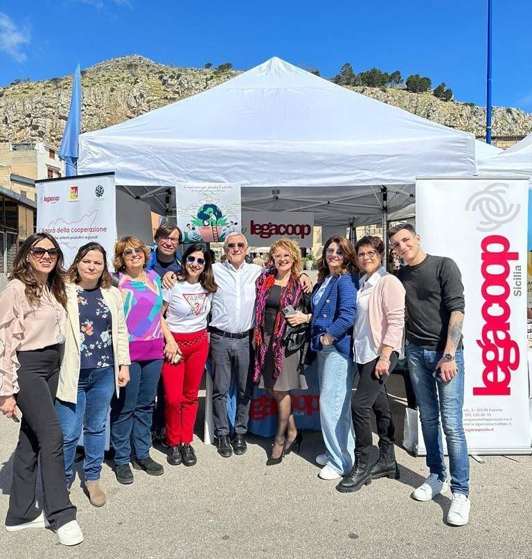 Un gruppo di persone posa per una foto davanti a una tenda bianca.